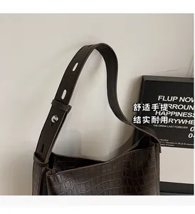 Detail of dark brown crocodile embossed shoulder bag with silver metal ring buckle