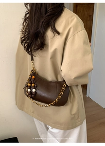Détail du sac demi-lune marron foncé rétro avec chaîne dorée et perles en bois