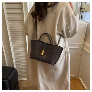 Detail view of large dark brown frosted tote bag with gold oval buckle and top handle