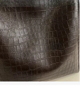 Close-up of deep brown embossed crocodile texture on the retro bucket bag leather