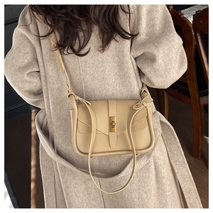 Détail du sac bandoulière minimaliste en cuir beige avec fermoir rotatif doré élégant