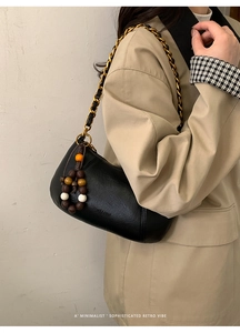 Détail du sac demi-lune noir mat avec bandoulière en chaîne dorée et perles vintage