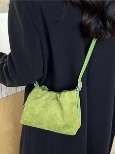 Green suede bucket bag with pleated design and adjustable strap shown on model