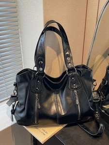 Classic black PU tote bag with silver studs and adjustable strap on a minimalist desk