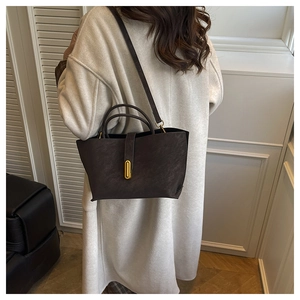 Detail view of large matte leather tote bag with elegant gold metal lock and long strap