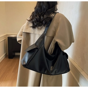 Detail of black leather tote bag featuring a functional side flap pocket and wide strap