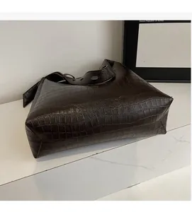 Detailed view of dark brown faux leather tote with embossed crocodile texture on marble