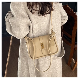 Elegante borsa beige a tracolla con chiusura dorata indossata su un lungo cappotto di lana