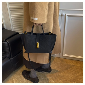 Detail of black matte leather tote bag featuring golden capsule magnetic clasp