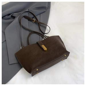Detail of dark brown matte tote bag with vintage gold metal buckle and sturdy bottom studs