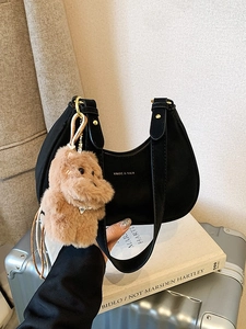 Black leather crescent underarm bag with teddy bear pendant and gold ring hardware