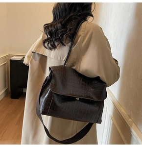 Side view of dark brown faux crocodile leather shoulder bag on a model in beige trench coat