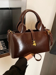 Dark brown patent leather top-handle bag with a gold gourd pendant and slim strap