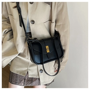 Détail du sac bandoulière en cuir noir mat minimaliste avec fermoir métallique doré chic