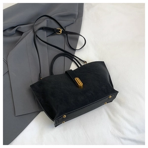 Detail of black frosted leather tote with vintage gold lock and protective metal rivets