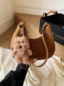 Brown semi-circle leather underarm bag with a cute plush dog charm and gold hardware