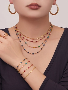 Detail showing colorful enamel pendants and stacked gold metal necklaces on model