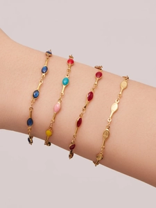 Detail view of four gold-plated colorful enamel and gemstone bracelets on a model wrist