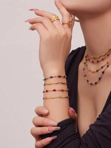 Close-up of colorful enamel jewelry with gold bracelets and layered beaded necklaces
