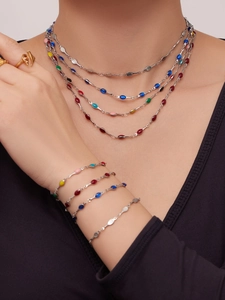 Detail of colorful enamel charms on stainless steel layered necklace and bracelet set