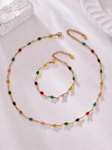 Macro detail of stainless steel necklace and bracelet set with colorful enamel oval charms