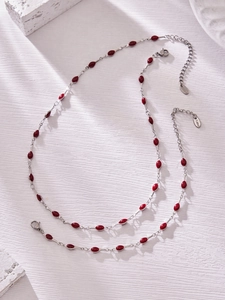 Detail of silver stainless steel necklace with red enamel teardrop charm and lobster clasp