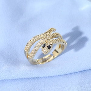 Detail of gold snake ring with micro-set zircons and black gemstone eyes on blue fabric