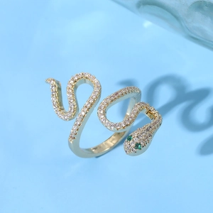 Detailed macro of golden cobra ring with sparkling zircons and green gemstone eyes