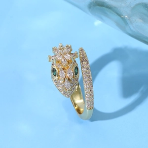 Luxurious gold cobra ring featuring sparkling diamonds, green gemstone eyes, and crown detail
