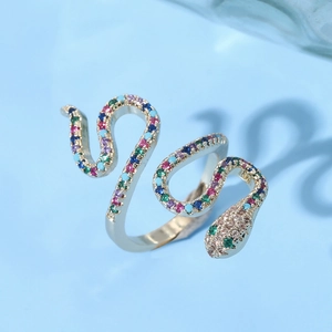 Golden snake ring with colorful zircon crystals on a light blue background