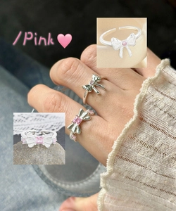 Close-up of S925 silver bow rings featuring pink zircon stones on model's hand