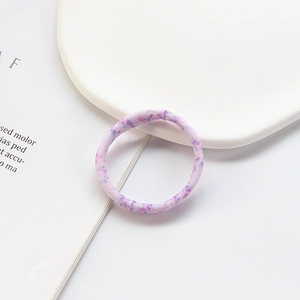 Detailed shot of a purple floral elastic hair tie on a white tray with lifestyle magazine