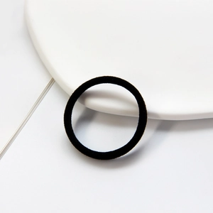 Detail of a high-elasticity black seamless hair tie on a white ceramic plate backdrop