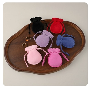 Macro view of velvet drawstring jewelry pouches in various colors on wooden tray