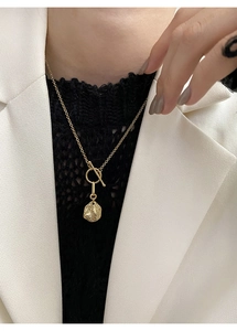 Detail of a gold S925 sterling silver necklace with OT buckle and textured coin pendant