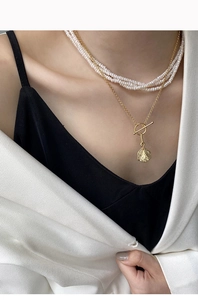 Detail of layered S925 silver necklace with white pearls, gold coin and vintage OT clasp