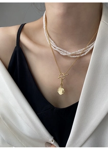 Detail of layered S925 silver pearl necklace with OT toggle clasp and hammered coin pendant