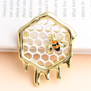 Eleganter Bienen und Waben Brosche aus Gold mit Emaille-Tropfen auf Vintage-Buchhintergrund