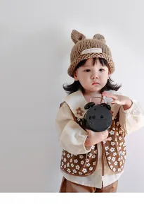 Detail of baby knit hat with bear ears and floral embroidered shirt for autumn