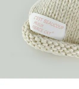 Macro shot of off-white chunky knit baby beanie showing detailed yarn texture and tag