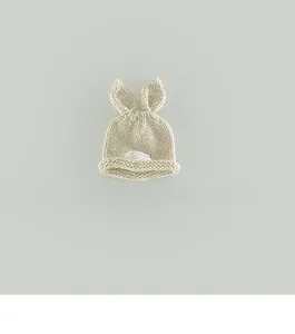 Detailed knit texture of off-white baby hat with rabbit ears and round fabric label