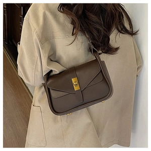 Détail du sac bandoulière en cuir marron foncé avec boucle dorée et pieds en métal