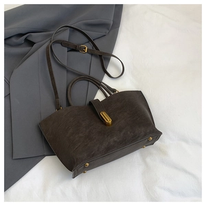 Detail of vintage matte brown leather tote featuring gold metal lock and bottom studs