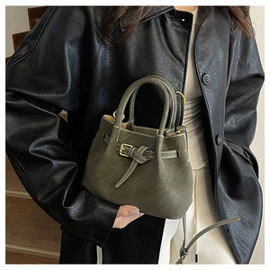 Detail of an olive green matte leather bucket bag with top handles and strap