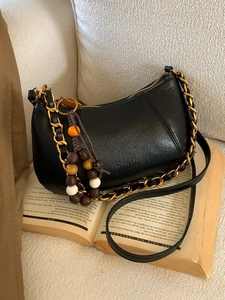 Sac bandoulière noir en forme de croissant avec texture grainée et breloque en perles