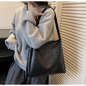 Model side view of vintage black crocodile textured bucket bag with slim shoulder strap