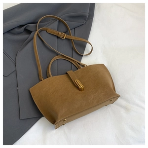 Flat lay of brown matte tote bag with gold buckle on grey blazer and white fabric