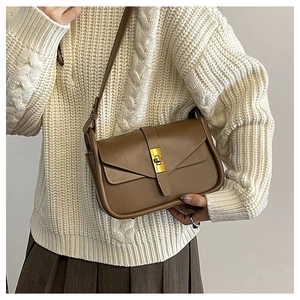 Borsa a tracolla in pelle marrone con fibbia dorata indossata con maglione autunnale