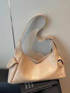 Minimalist beige faux leather tote bag with side pockets and adjustable shoulder strap