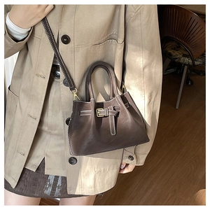 Close-up of brown leather bucket bag with white contrast stitching and gold hardware
